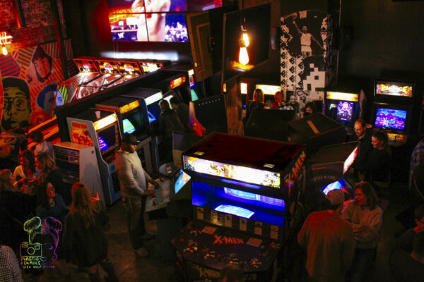 A spacious arcade filled with various machines and people engaged in playing games A spacious arcade filled with various machines and people engaged in playing games