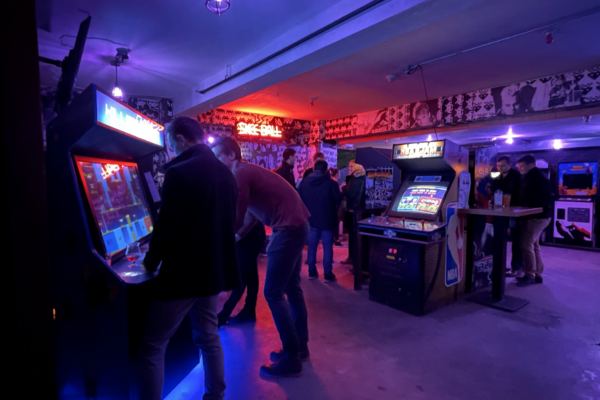 Several individuals in a room, focused on playing video games, with controllers in hand and screens displaying gameplay. Several individuals in a room, focused on playing video games, with controllers in hand and screens displaying gameplay.