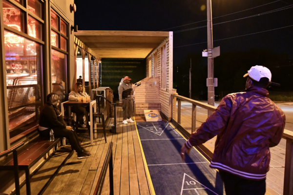 A man playing a game on a brightly lit boardwalk at night, surrounded by colorful lights and a lively atmosphere A man playing a game on a brightly lit boardwalk at night, surrounded by colorful lights and a lively atmosphere