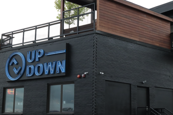 A low-angle shot of the Up-Down bar, showcasing its black brick exterior and blue neon sign A low-angle shot of the Up-Down bar, showcasing its black brick exterior and blue neon sign