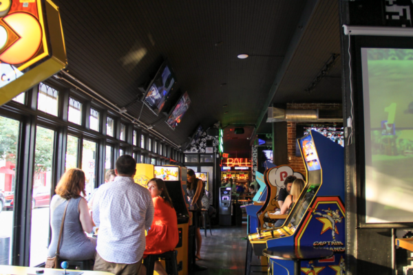 A blurry interior shot of a bar, showing a long hallway lined with a variety of arcade games. A blurry interior shot of a bar, showing a long hallway lined with a variety of arcade games.