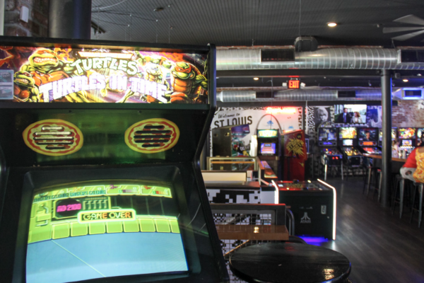 A close-up of a Teenage Mutant Ninja Turtles arcade machine in the foreground of a blurry arcade room. A close-up of a Teenage Mutant Ninja Turtles arcade machine in the foreground of a blurry arcade room.