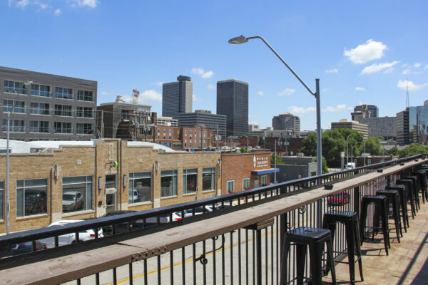 A balcony overlooking a vibrant city skyline, showcasing tall buildings against a clear blue sky A balcony overlooking a vibrant city skyline, showcasing tall buildings against a clear blue sky