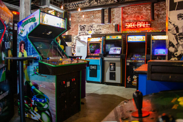An arcade room showcasing multiple games alongside a wall adorned with striking graffiti art An arcade room showcasing multiple games alongside a wall adorned with striking graffiti art