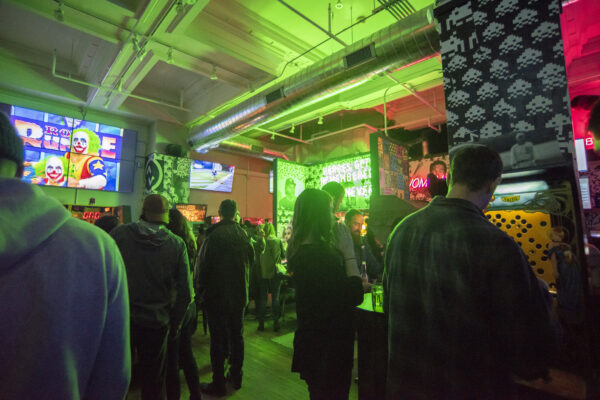 A bustling bar scene with a crowd of patrons under glowing green lights A bustling bar scene with a crowd of patrons under glowing green lights