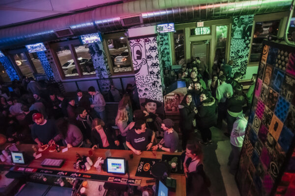 A lively crowd of people socializing in a bar illuminated by vibrant neon lights. A lively crowd of people socializing in a bar illuminated by vibrant neon lights.